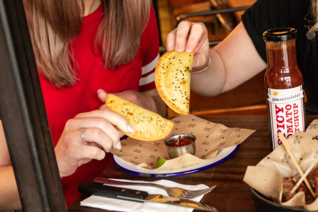 Two people eating Pieminister vegan patties