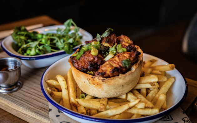 Plated pie on top of chips with side of greens