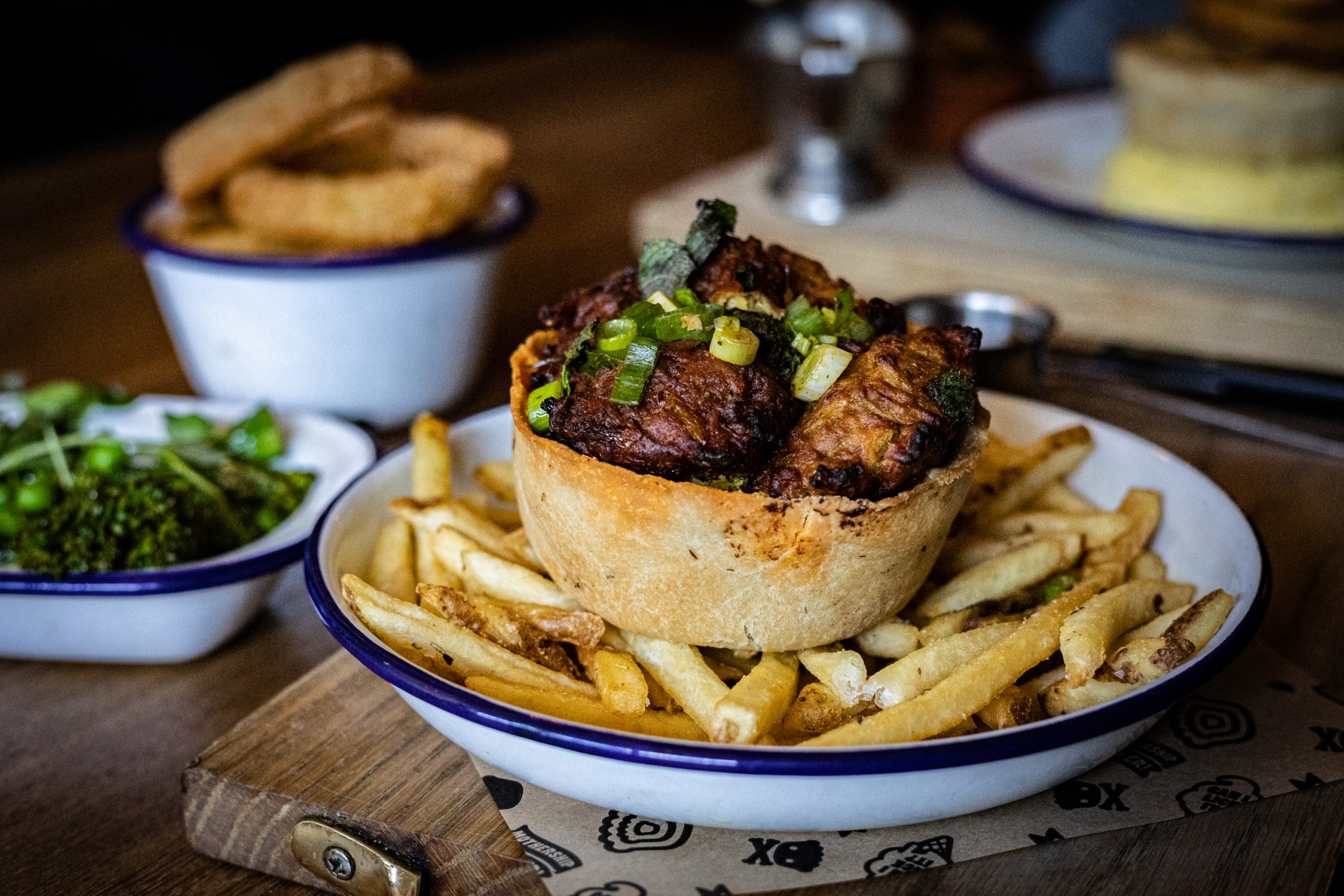 close up of onion bhaji on top of chicken pie and fries